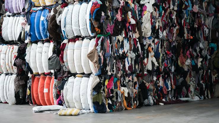 Compressed bales of discarded fabrics and garments stacked for textile sorting